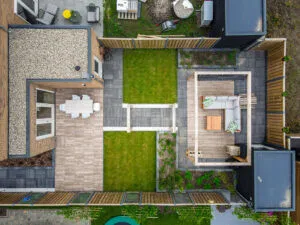 Drone-bovenaanzicht van een aangelegde tuin met terras, gazonvlakken, plantvakken en buitenverblijf