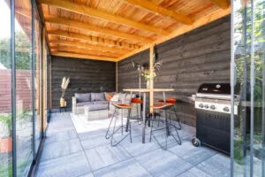 Overdekt buitenverblijf met houten plafond, gas-BBQ, bartafel met krukken en loungeset