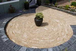 Ronde sierbestrating in cirkelpatroon van gele klinkers, met zwarte sierpot in het midden